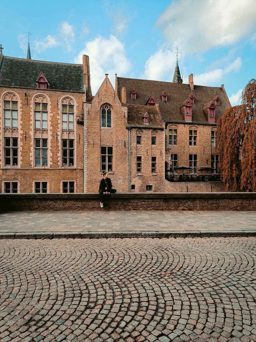 a-person-sitting-on-a-bench-in-front-of-a-building-pfnphgebmeg
